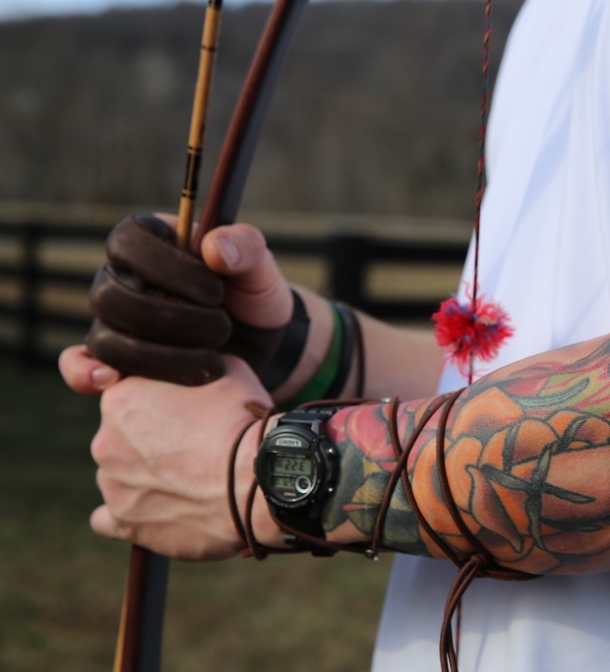 A tattooed arm holding a bow